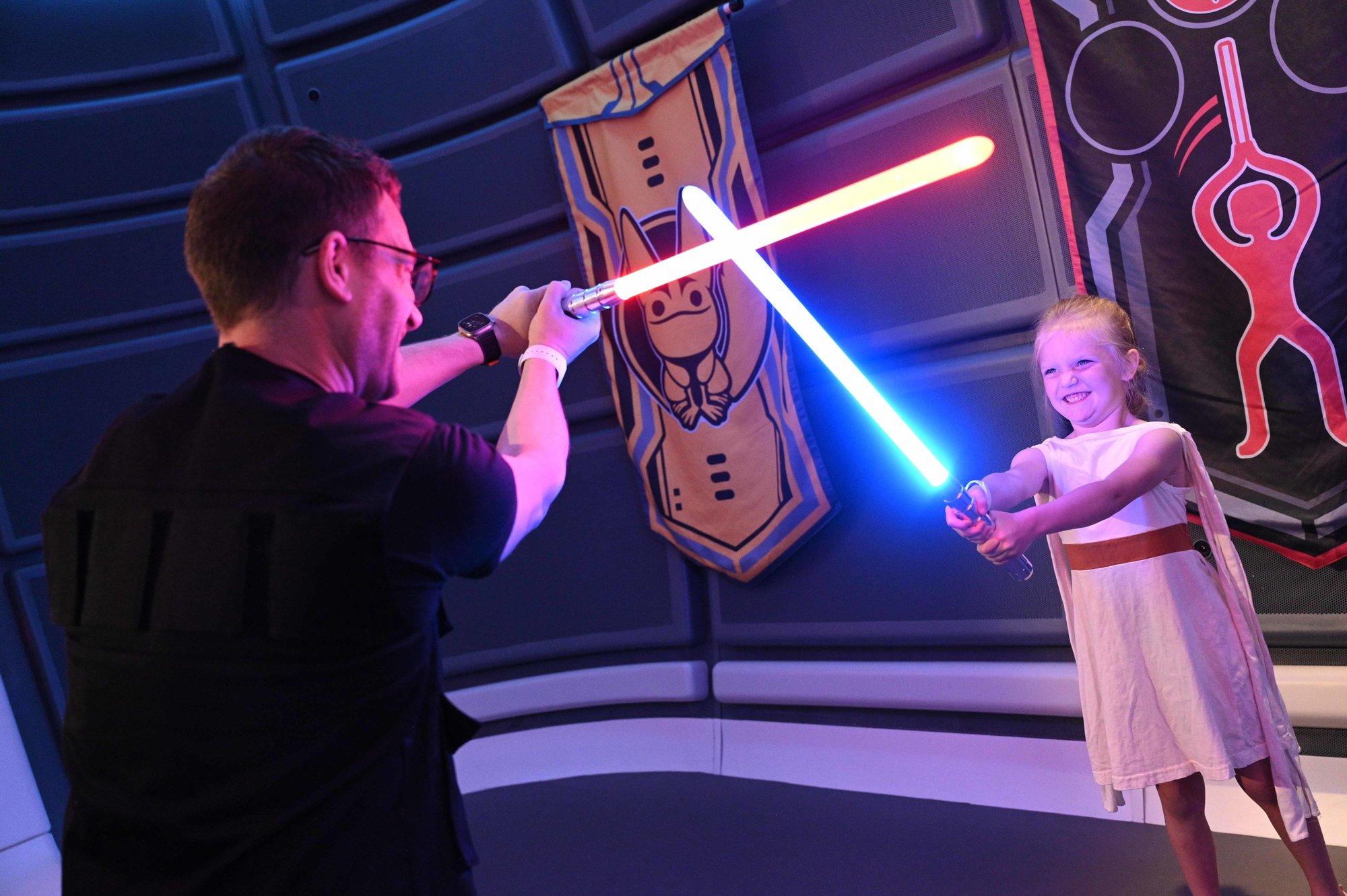 man and child battling with blue and red lightsabers